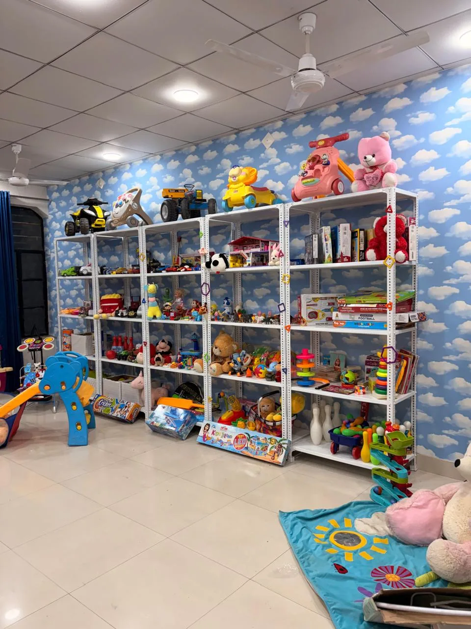 Shelves at Chahak with ride-on toys on top, soft toys, board games and science kits