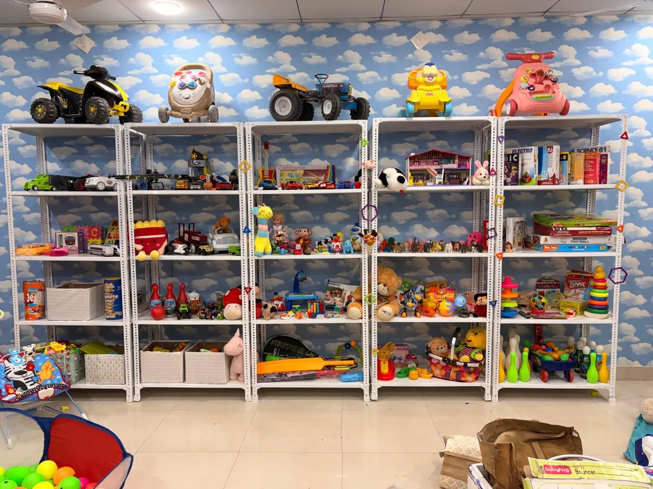 A full wall of shelves with ride-on toys on top and toys sorted below
